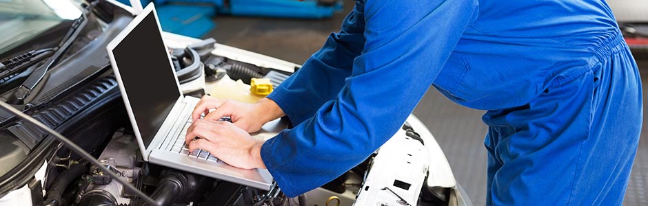 mechanic using a laptop for diagnostic testing on a vehicle